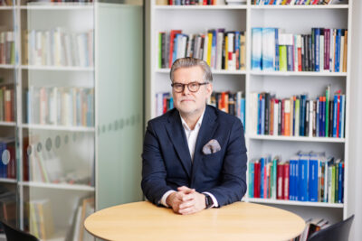 Vakavailmeinen mies istuu pöydän äärellä.