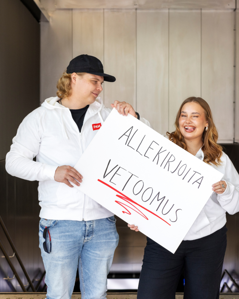 Kuvassa kaksi PAMin ohjausryhmän nuorta pitävät käsissään kampanjakylttiä, jossa lukee "allekirjoita vetoomus".