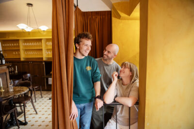 Kuvassa vasemmalla ravintoloitsija Tom Hansen, keskellä tarjoilja Leif Halverson ja oikealla ravintoloitsija Laura Styyra. Henkilöt katsovat toisiaan hymyillen.