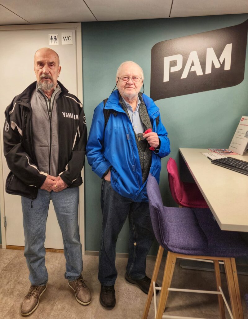 kaksi henkilöä PAMin logon edessä