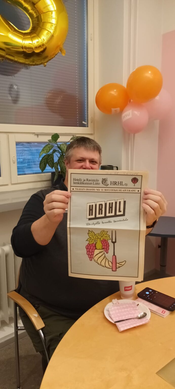 mies pitää lehteä kädessä