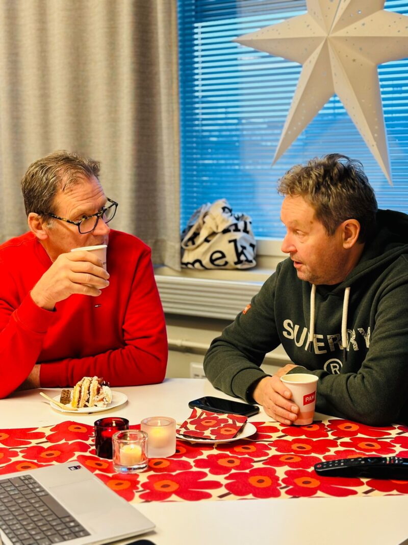 Kaksi henkilöä istuu pöydän ääressä ja juttelee