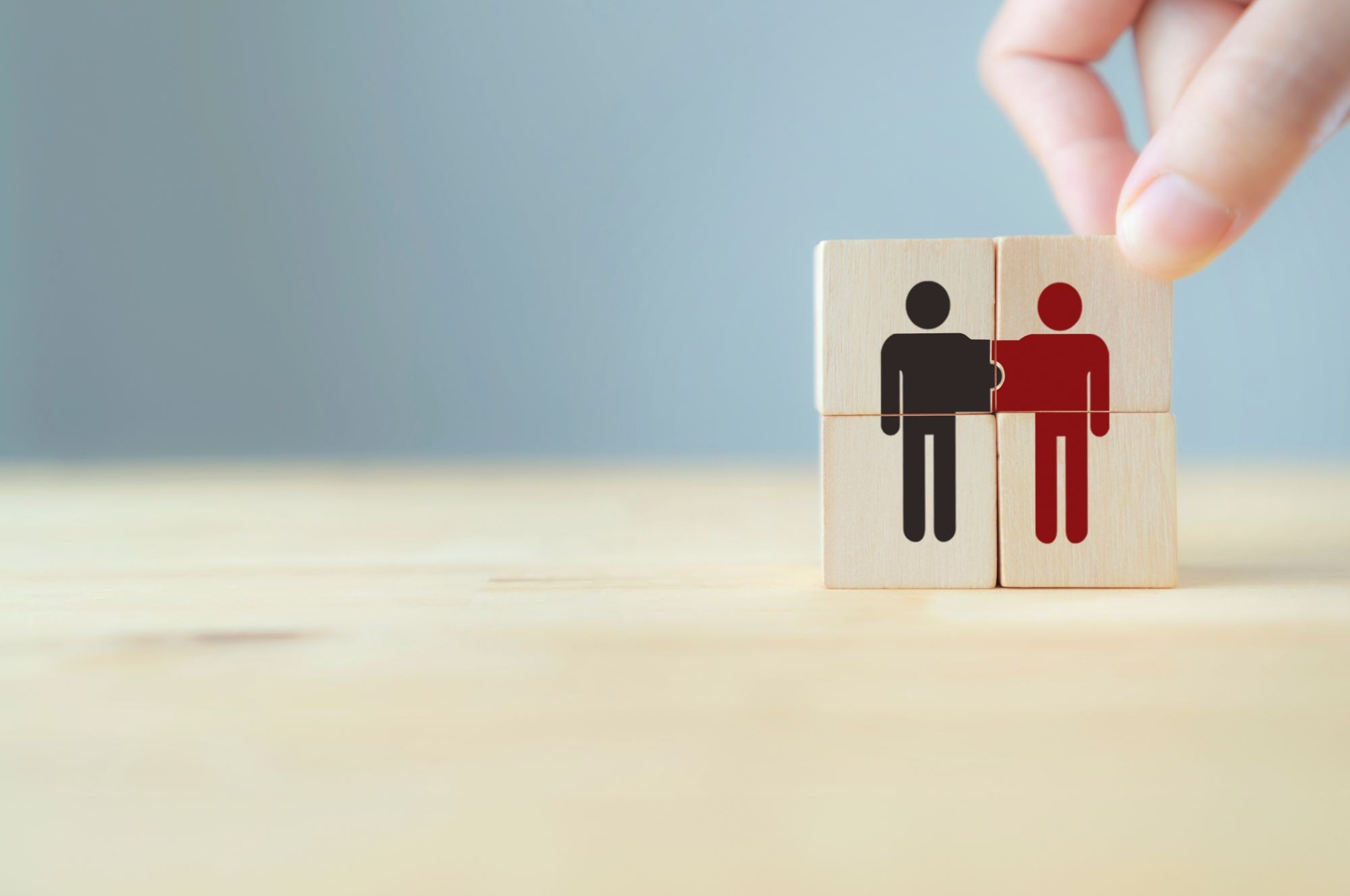 Kuvassa kaksi puista palikkaa, joissa on henkilöitä kuvaavat eriväriset ikonit.