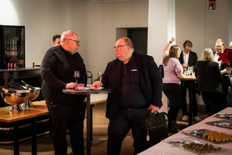 kaksi henkilöä nojaa pöytään. 