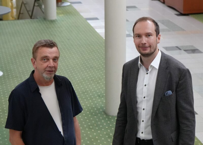 Kaksi miestä katsoo kameraan