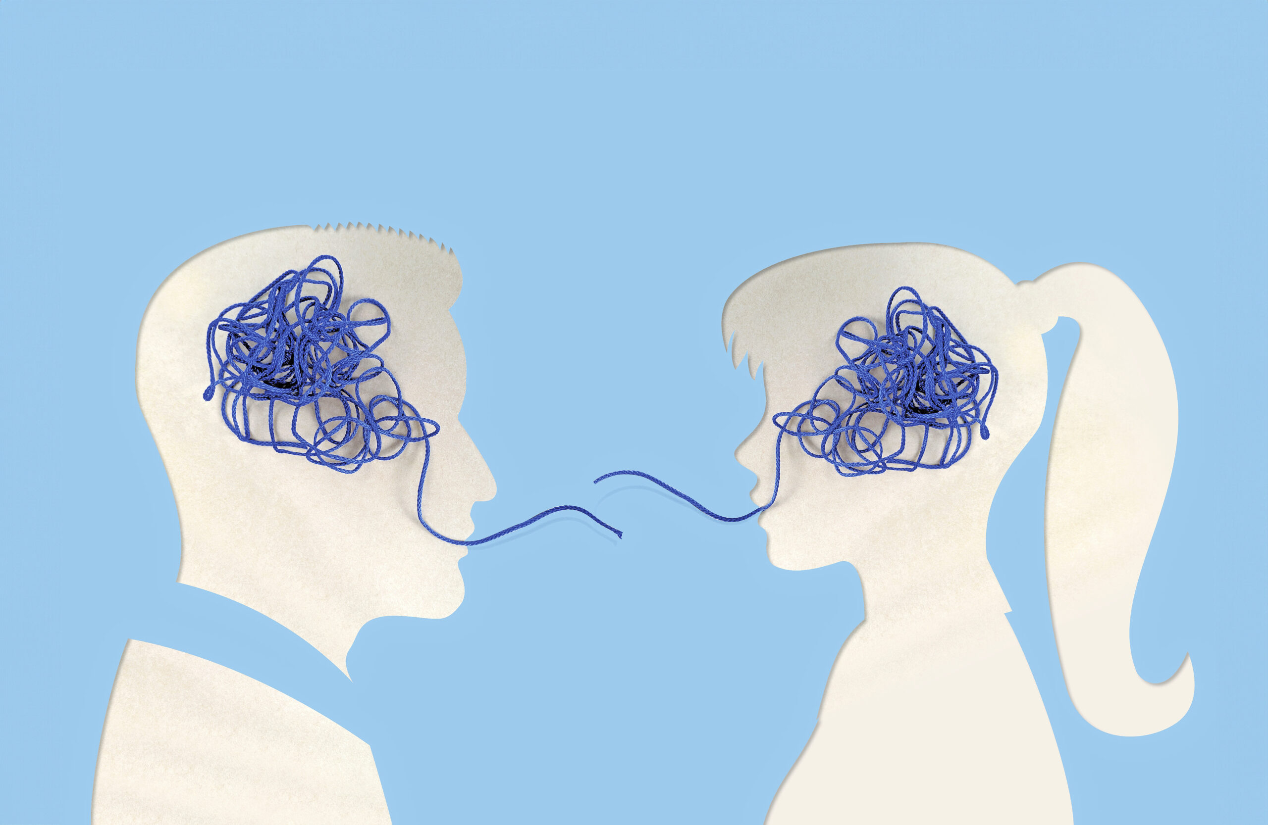 Kaksi paperileikkaustyylistä profiilia vastakkain vaaleansinistä taustaa vasten; miehen ja naisen päässä siniset sotkuiset langat, jotka yhdistyvät ohuella langanpätkällä – kuvaa kommunikaatio-ongelmia ja vaikean keskustelun tarvetta.