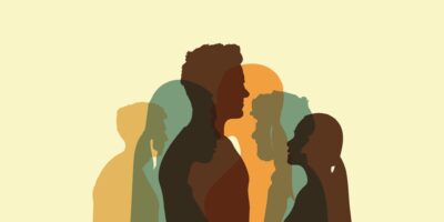 Useita päällekkäisiä ihmissiluetteja eri kokoisina ja eri väreissä vaaleankeltaisella taustalla; kuva symboloi yhteisöä, moninaisuutta ja yhdessä tekemistä.