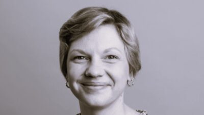 Hymyilevä lyhyttukkainen nainen mustavalkoisessa kuvassa.